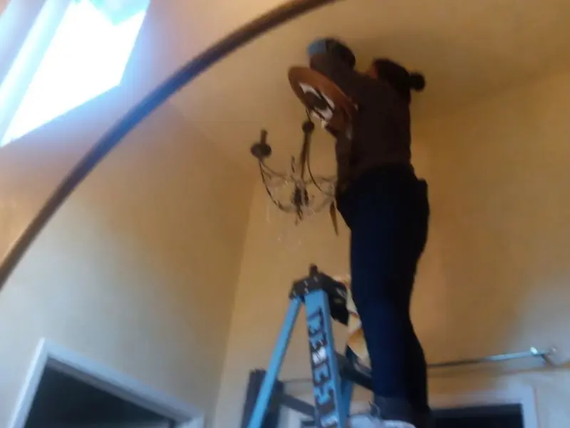 Electrician installing a chandelier in a Sheridan residence